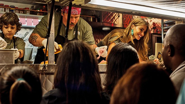 Chef. Descrição da imagem: família cozinhando dentro do trailer e pessoas aguardando do lado de fora.