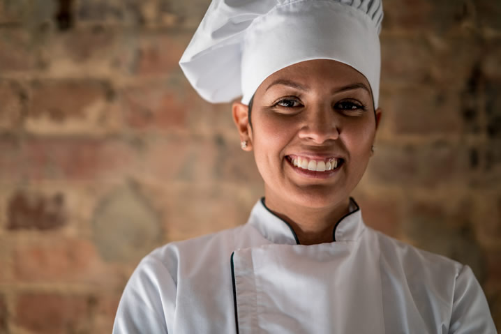 Profissão Gastronomia. Descrição da imagem: moça vestida como chef de cozinha.